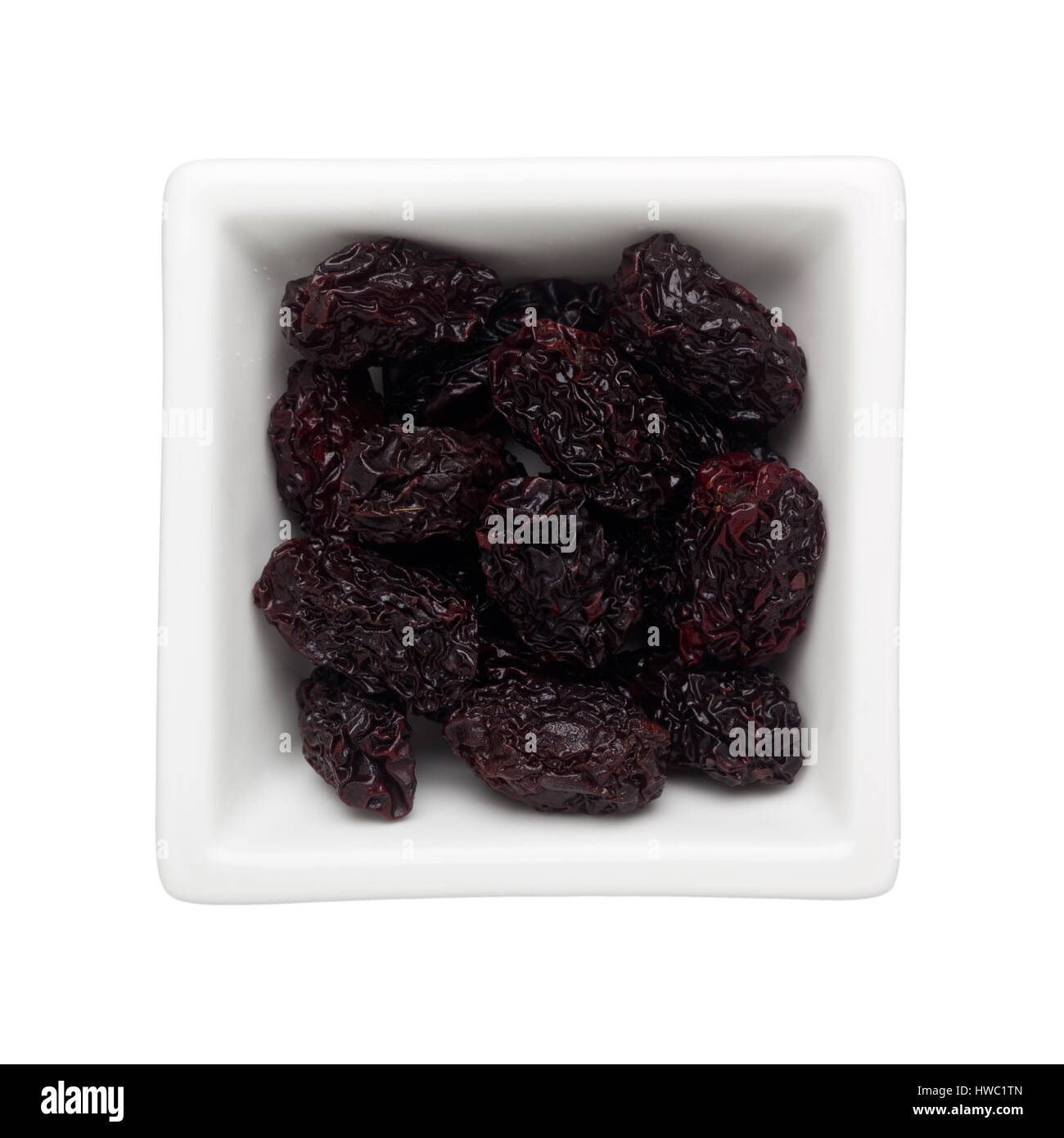 Dried black dates in a square bowl isolated on white background Stock Photo
