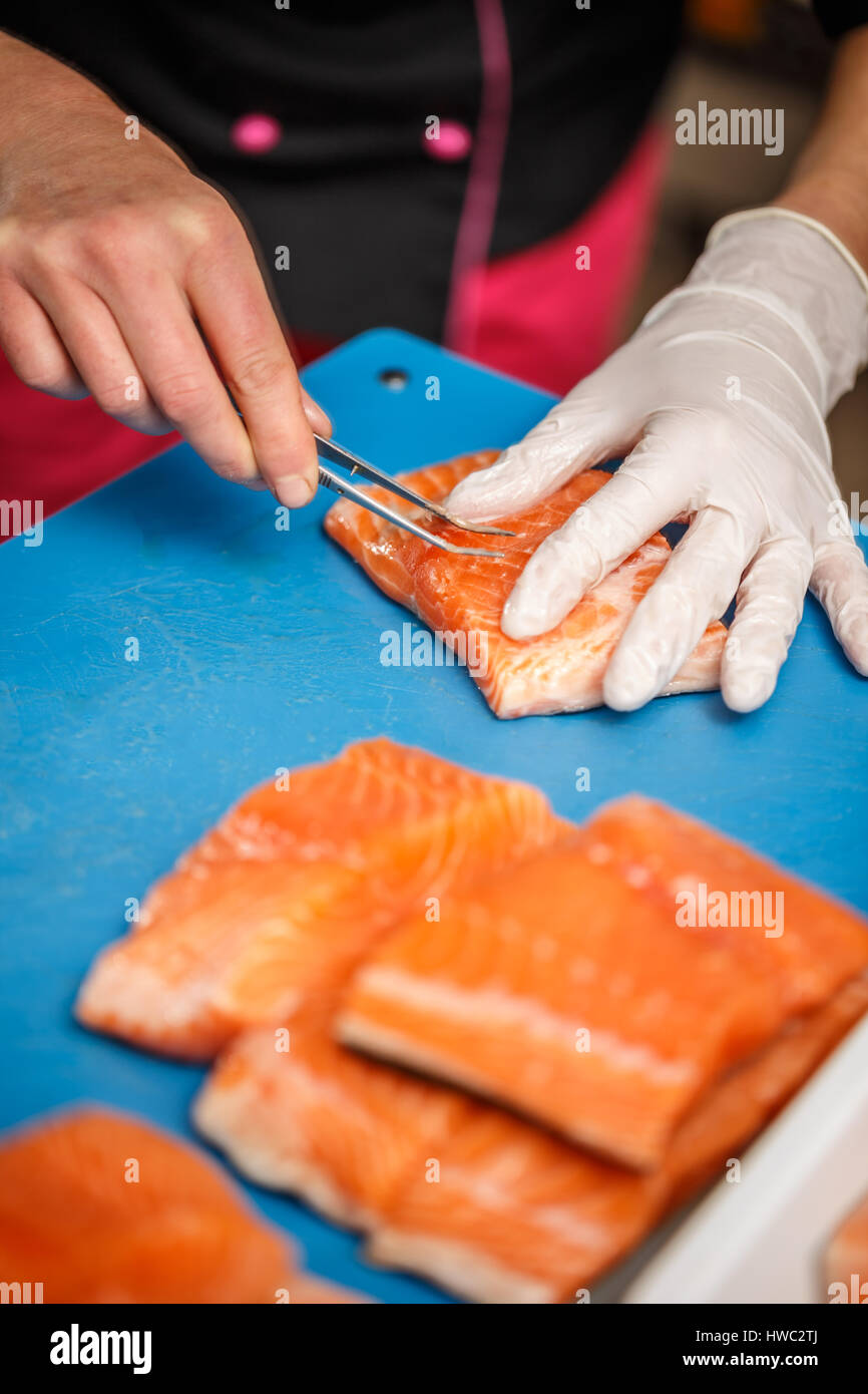Chef is removing fish bone from salmon with tweezer Stock Photo