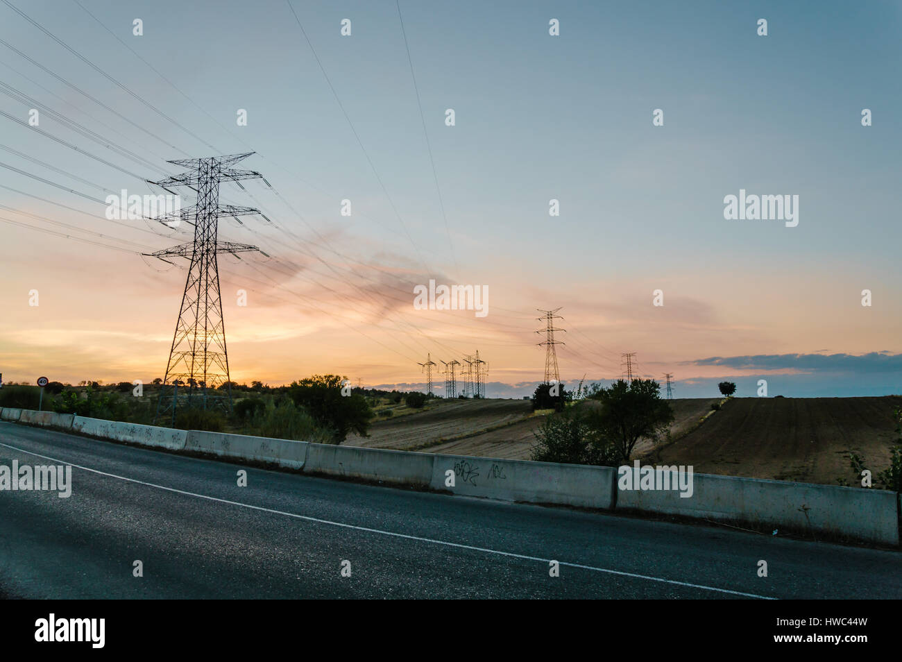 Road against high voltage towers at sunset Stock Photo - Alamy