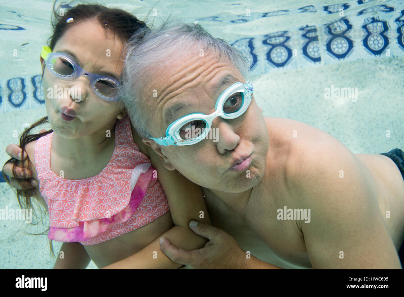 Senior underwater in a swimming pool with granddaughter Stock Photo