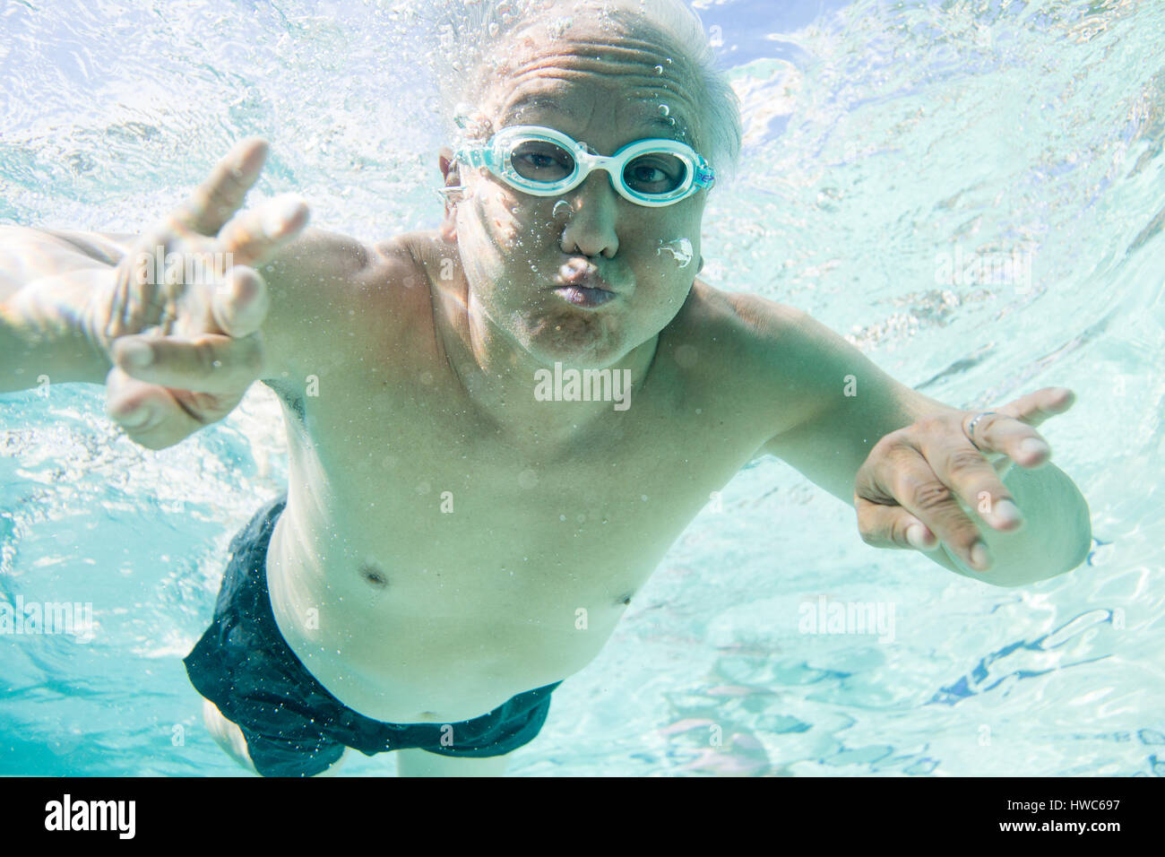 Senior being silly underwater in a swimming pool Stock Photo