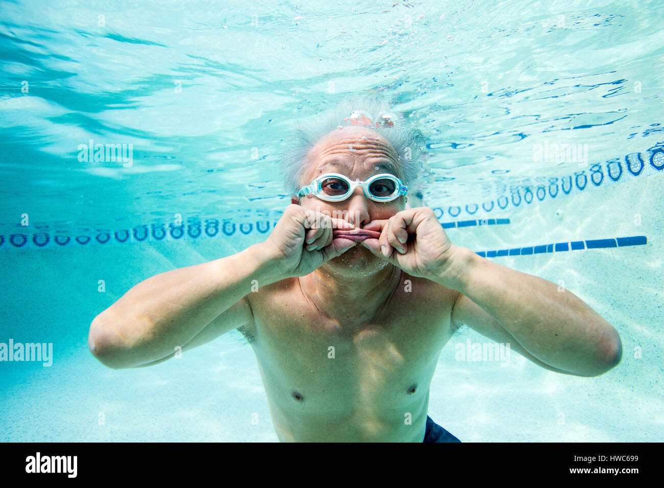 Senior being silly underwater in a swimming pool Stock Photo