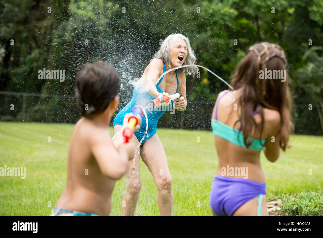 Grandmother playing with grandchildren with waterguns Stock Photo