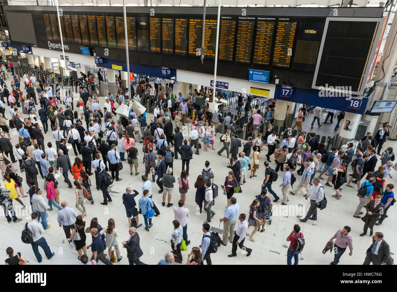 Crowds of passengers in front of the train departure board at Waterloo Railway Station, London, England, UK Stock Photo