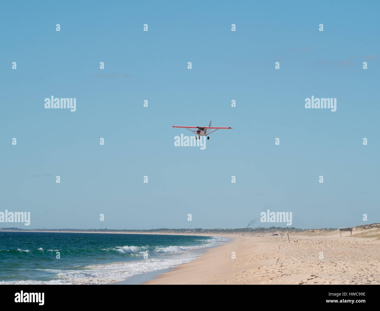 Small airplane flies over an empty beach Stock Photo