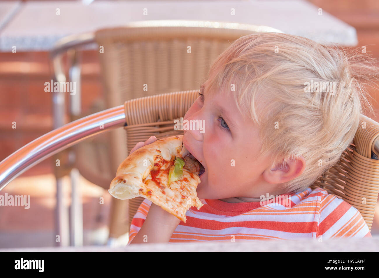 Child eats pizza in cafe, tinted photo. Stock Photo