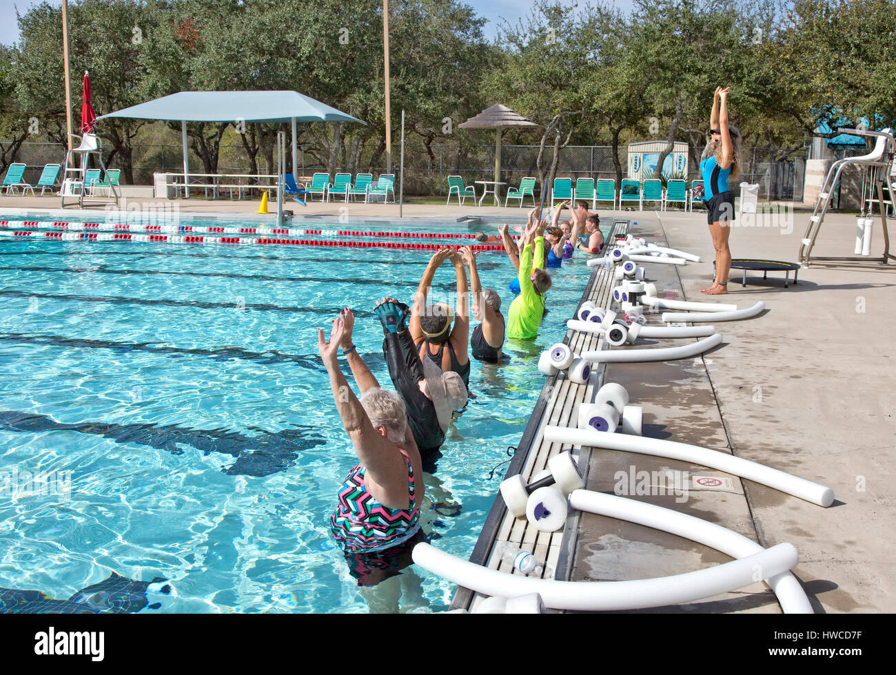 Group of women (various ages) attending Water Aerobics Class, instructor demonstrating 'proper