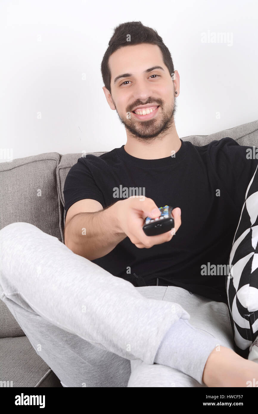 Attractive young man watching tv and relaxed on couch. Indoors. Stock Photo