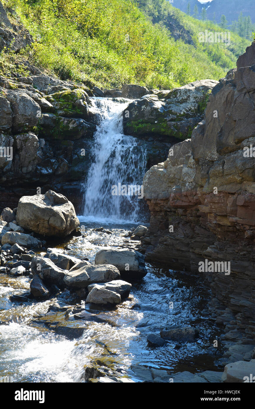 Waterfall among the rocks on the Putorana plateau. Mountain landscape ...