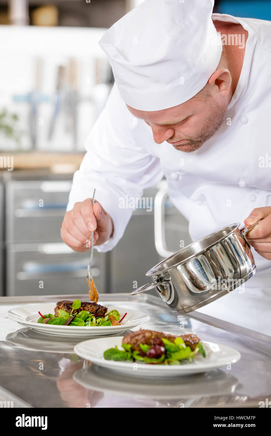 Focused professional chef prepare meat dish at restaurant Stock Photo