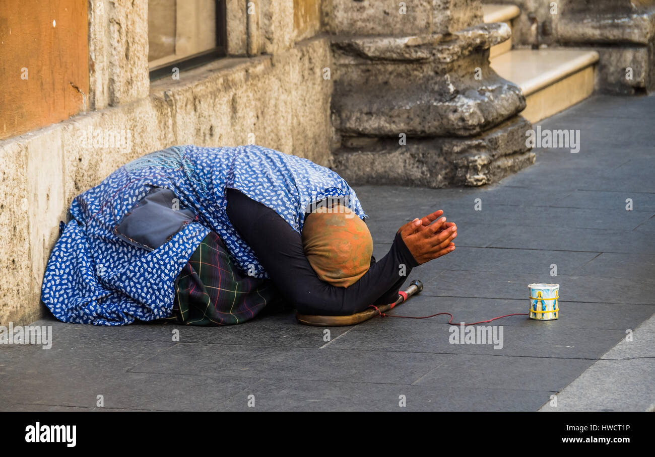 A beggar on the street. Anti-theft device by means of red cable, Eine Bettlerin auf der Straße. Diebstahlsicherung mittels rotem Kabel Stock Photo