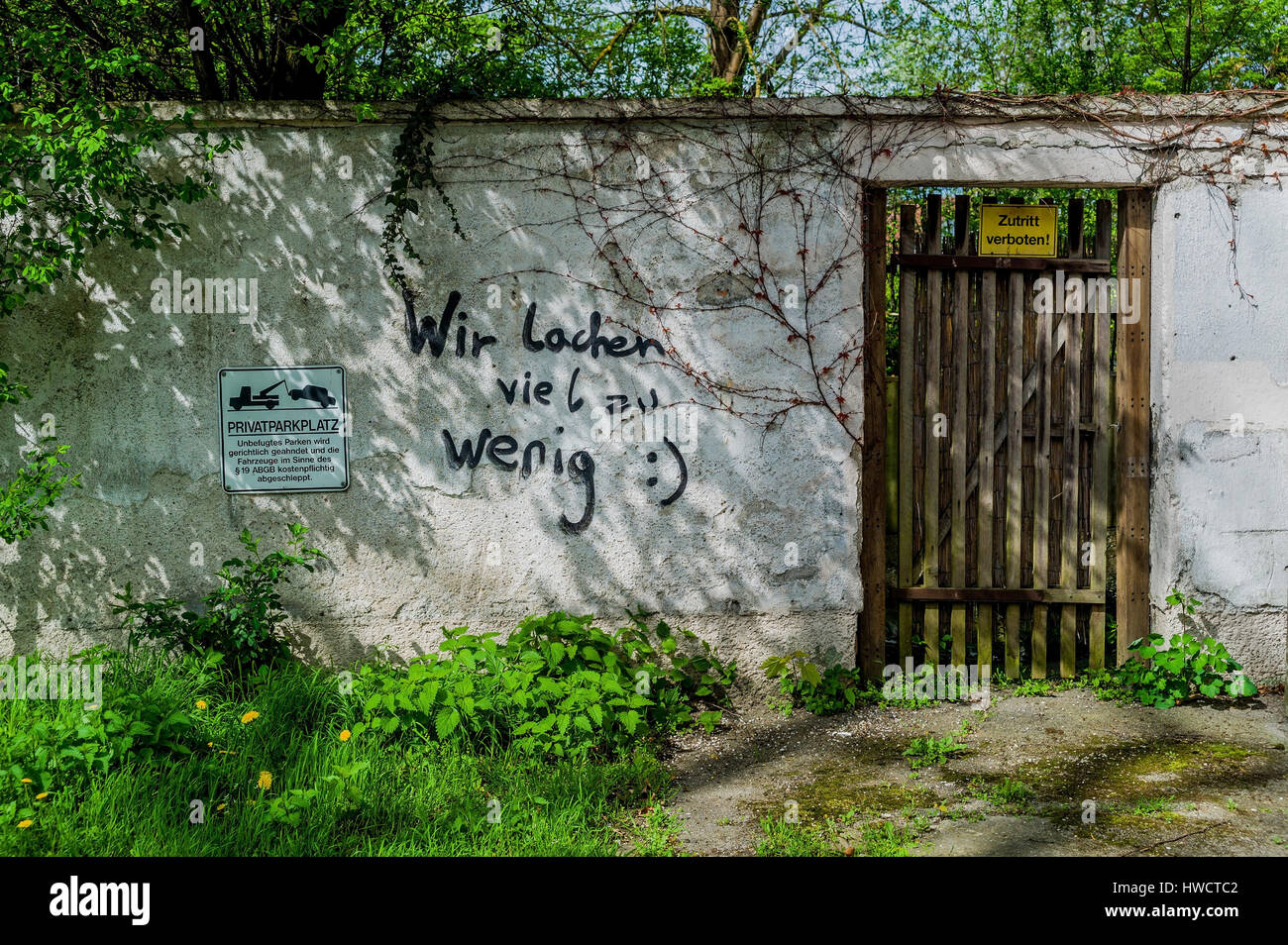 Label on a wall, we laugh too little, Aufschrift auf einer Mauer, wir lachen viel zu wenig Stock Photo