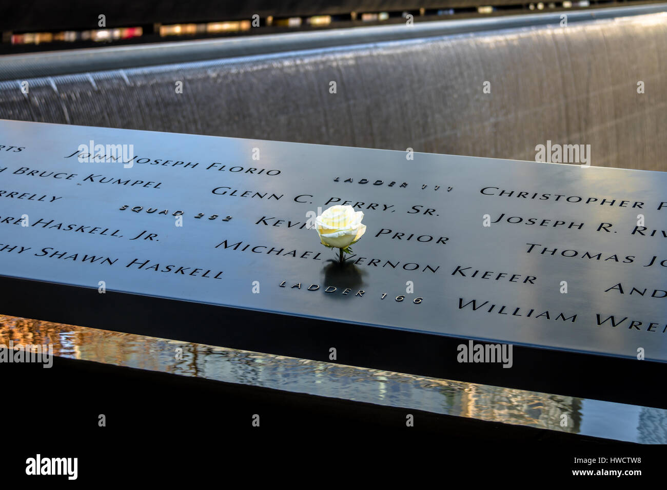 Birthday white rose left near name of victim engraved on bronze parapet of 9/11 Memorial at World Trade Center Ground Zero  - New York, USA Stock Photo