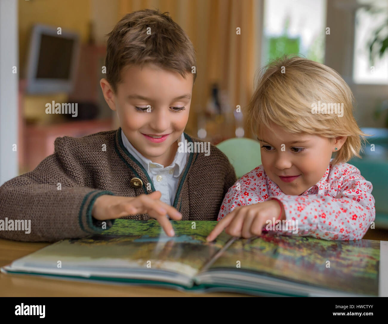 Two children have a look together at a book, Zwei Kinder sehen sich zusammen ein Buch an Stock Photo