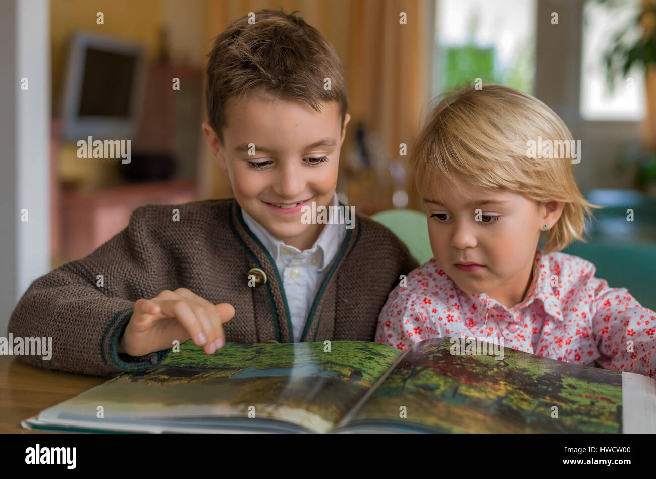 Two children have a look together at a book, Zwei Kinder sehen sich zusammen ein Buch an Stock Photo
