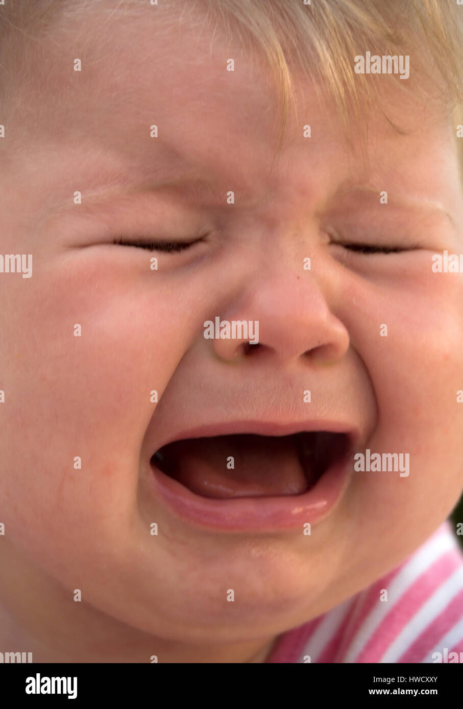 Crying baby lies on a meadow and is sad, Weinendes Baby liegt auf einer Wiese und ist traurig Stock Photo