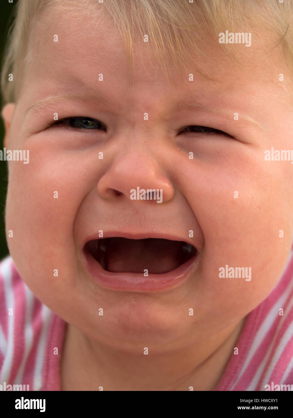 Crying baby lies on a meadow and is sad, Weinendes Baby liegt auf einer Wiese und ist traurig Stock Photo