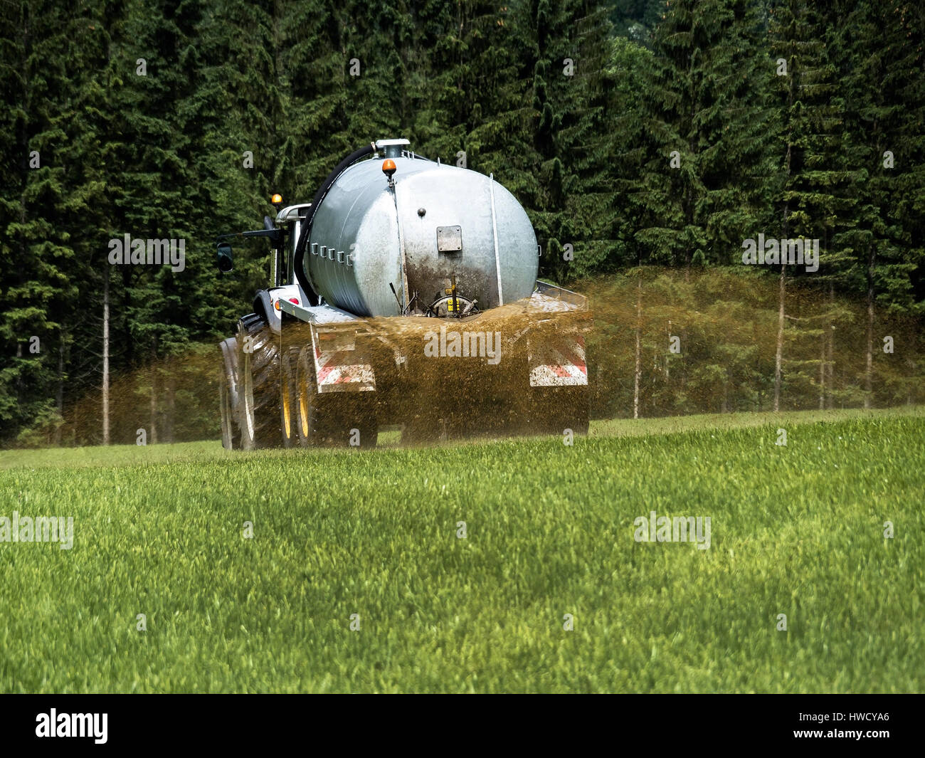 A farmer goes with liquid manure on a field for fertilising, Ein Bauer fährt mit Gülle auf einem Feld zum Düngen Stock Photo