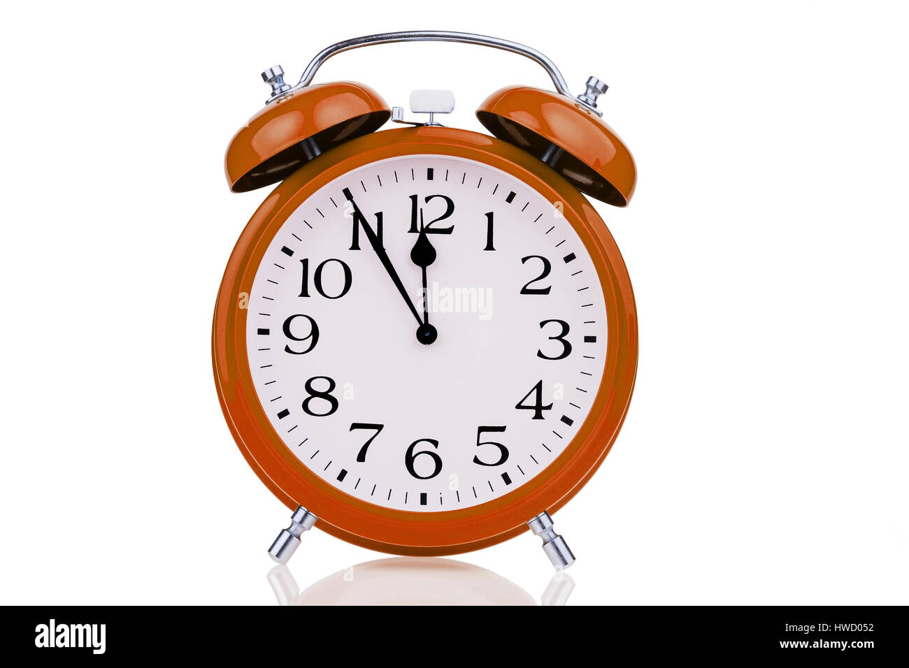 A red alarm clock on white background. Five before twelve, Ein roter Wecker auf weissem Hintergrund. Fuenf vor Zwoelf Stock Photo
