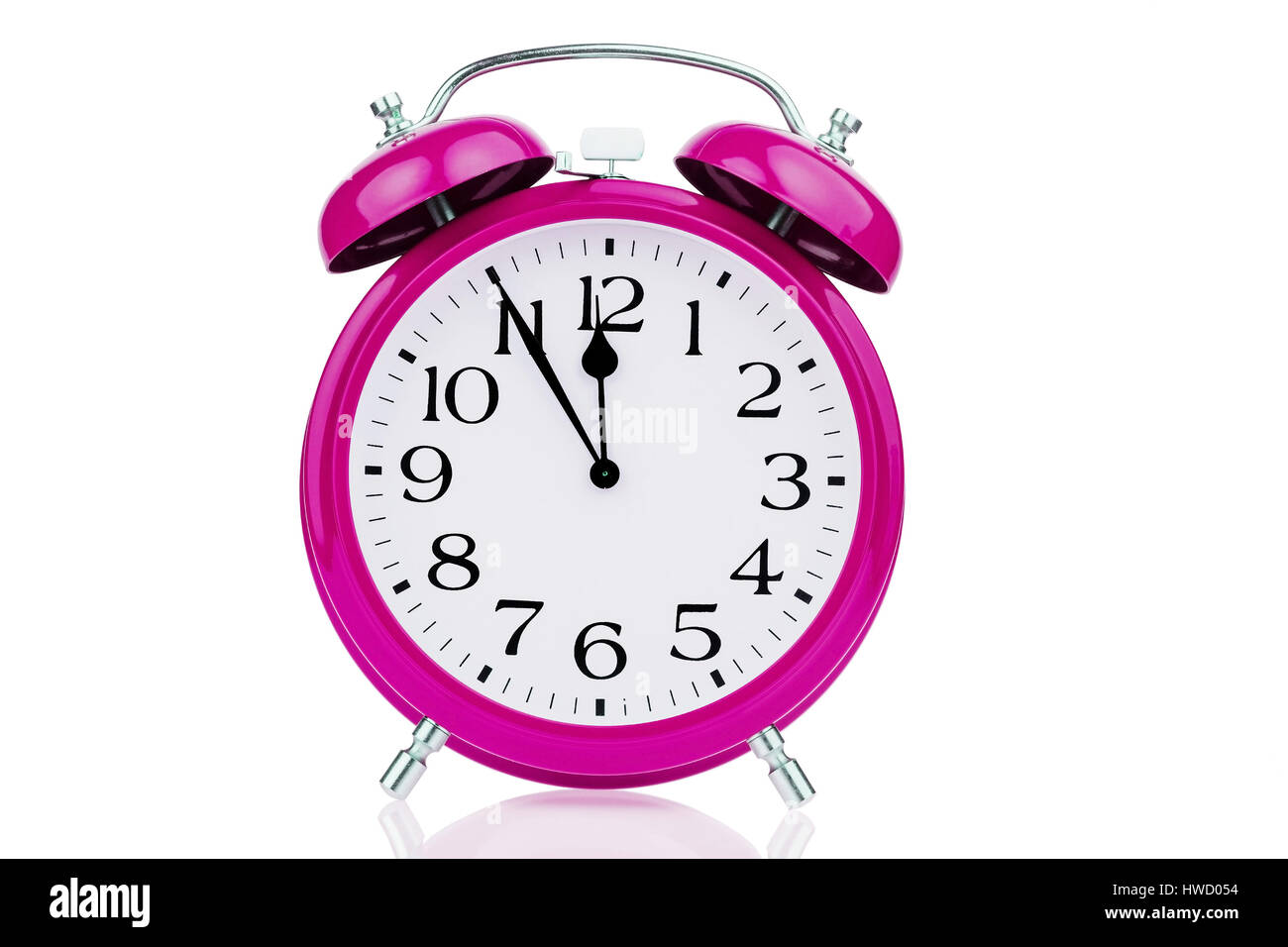 A pink alarm clock on white background. Five before twelve, Ein rosa Wecker auf weissem Hintergrund. Fuenf vor Zwoelf Stock Photo