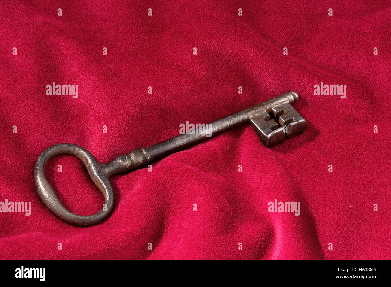 A key lies on a red velvet cushion. Symbolic photo for key handing over at enterprise., Ein Schluessel liegt auf einem roten Samtkissen. Symbolfoto fu Stock Photo