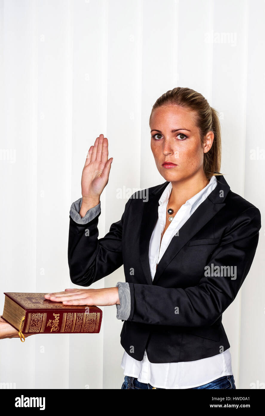 A woman states as a witness at court in a court procedure. Is sworn in and swears on the Bible., Eine Frau sagt als Zeuge bei Gericht in einem Gericht Stock Photo