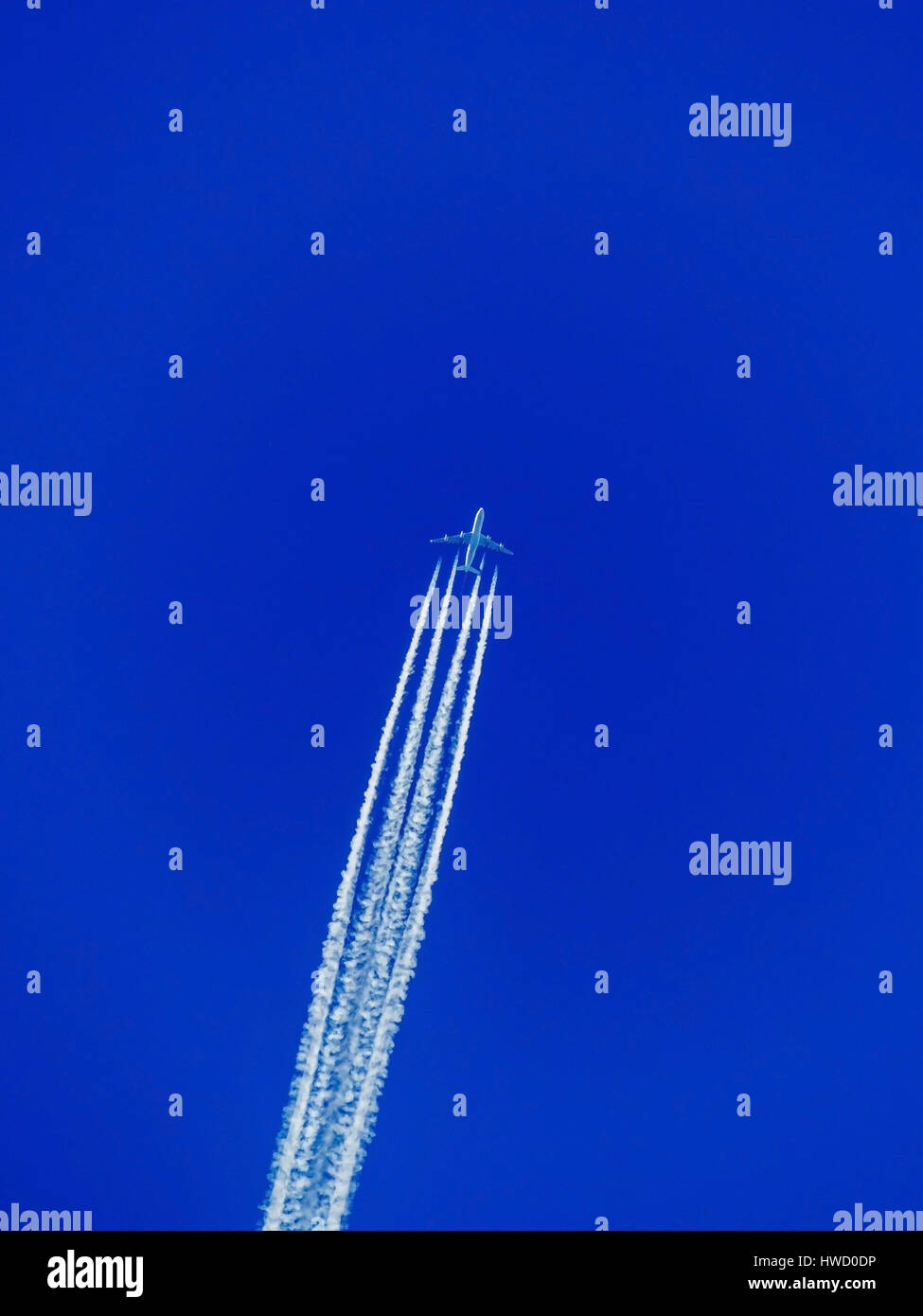 An airplane with condensation trail before the blue sky. Flight in the vacation, Ein Flugzeug mit Kondensstreifen vor dem blauen Himmel. Flugreise in  Stock Photo