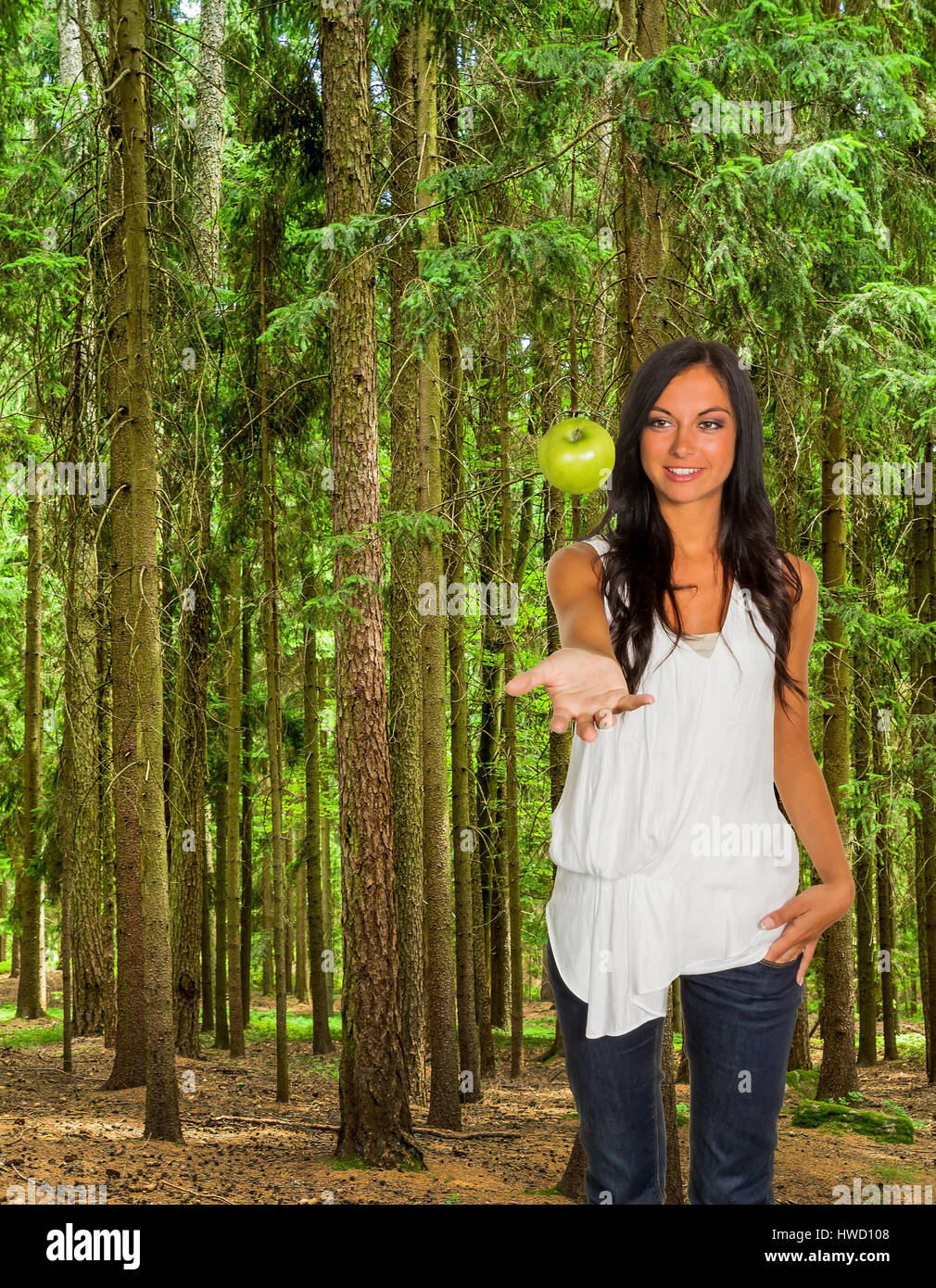 Many trees in a wood with fresh green and a woman with an apple, Viele Bäume in einem Wald mit frischem Grün und einer Frau mit einem Apfel Stock Photo