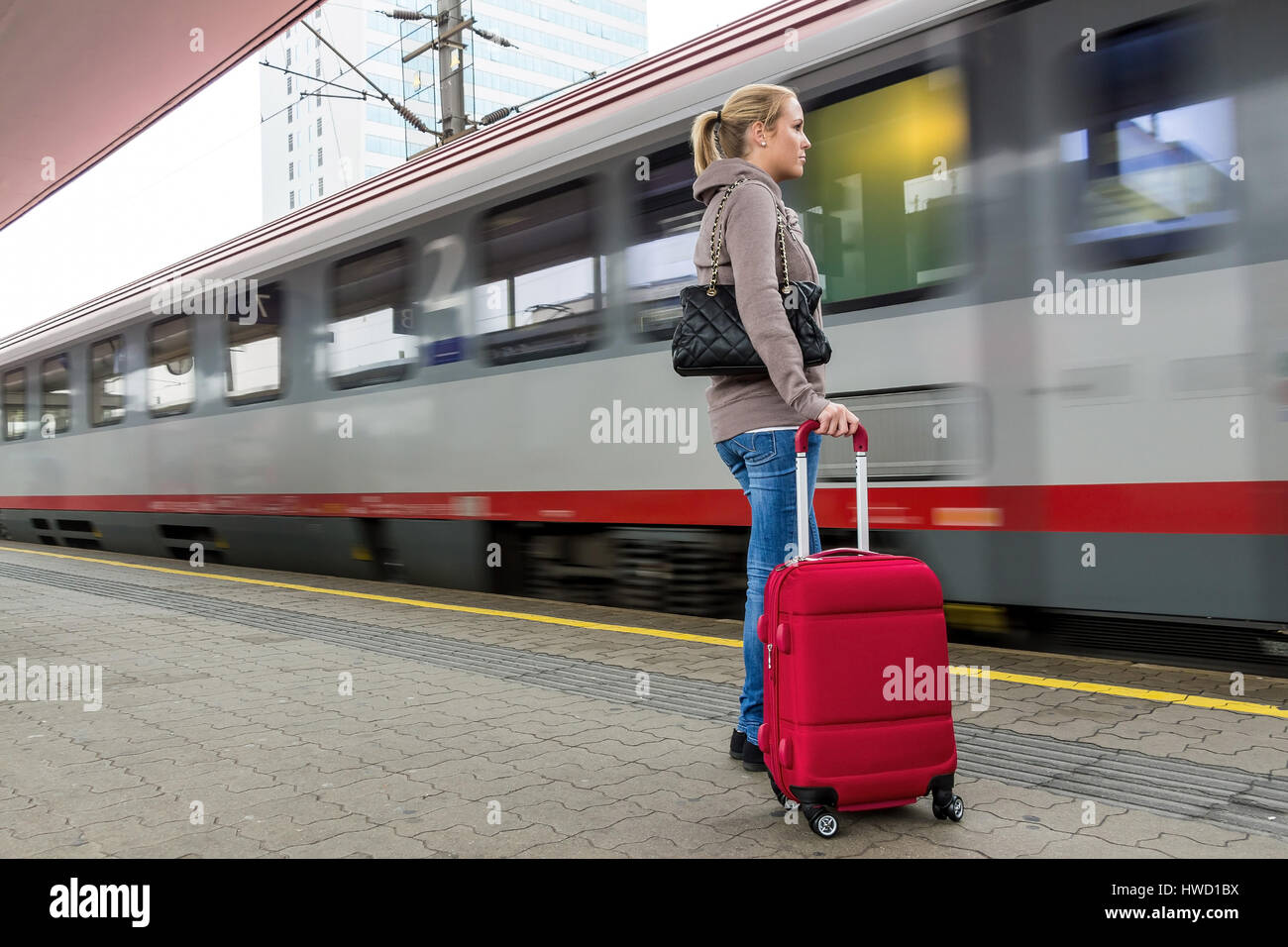 A young woman waits for a train in a railway station. Train journey in the vacation, Eine junge Frau wartet auf einen  Zug in einem Bahnhof. Zugfahrt  Stock Photo