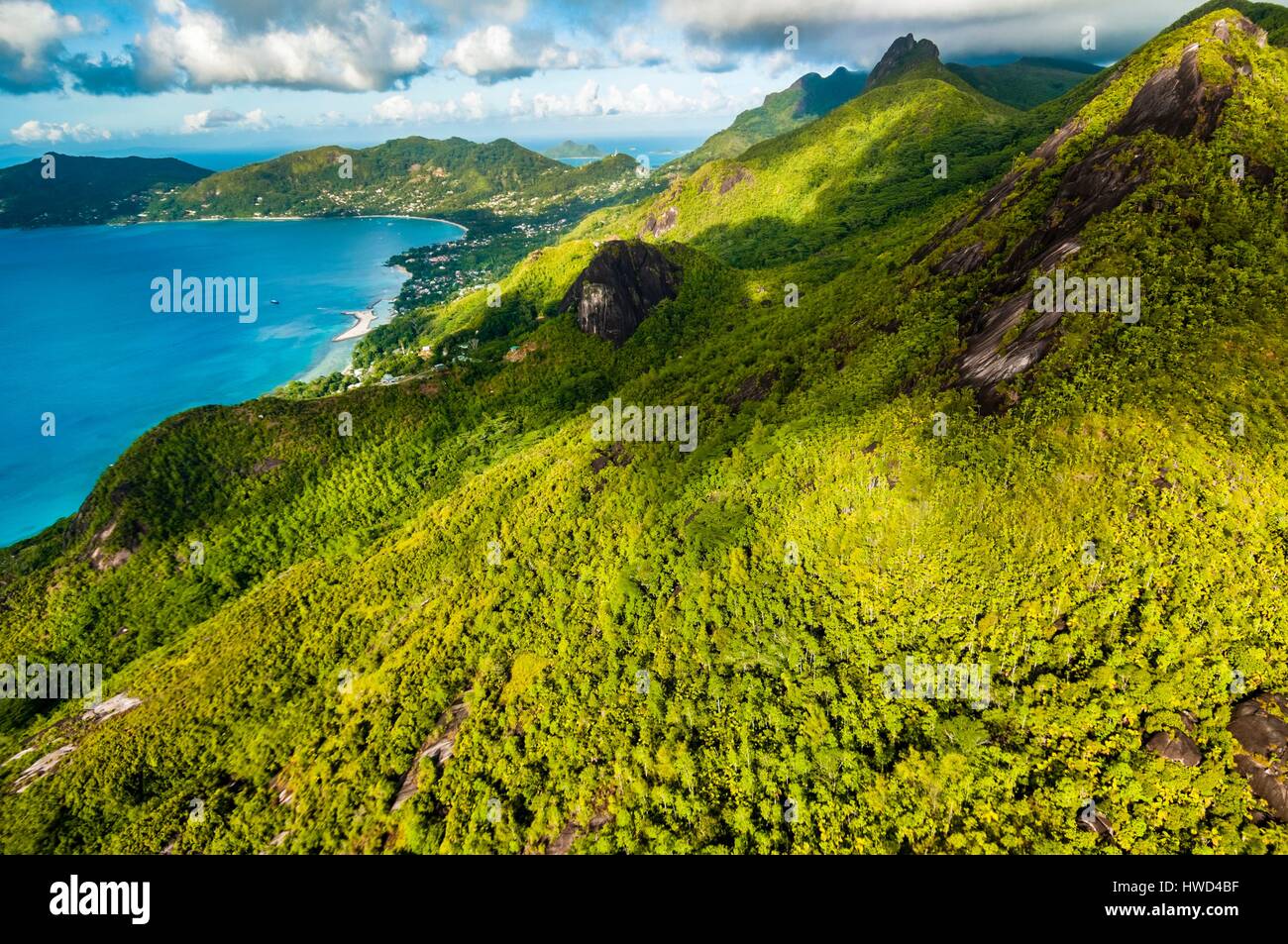 Seychelles, Mahe island, the rainforest and granite cliffs of the Morne Seychellois National Park with the villages of Bel Ombre and Beau Vallon in the background (aerial view) Stock Photo