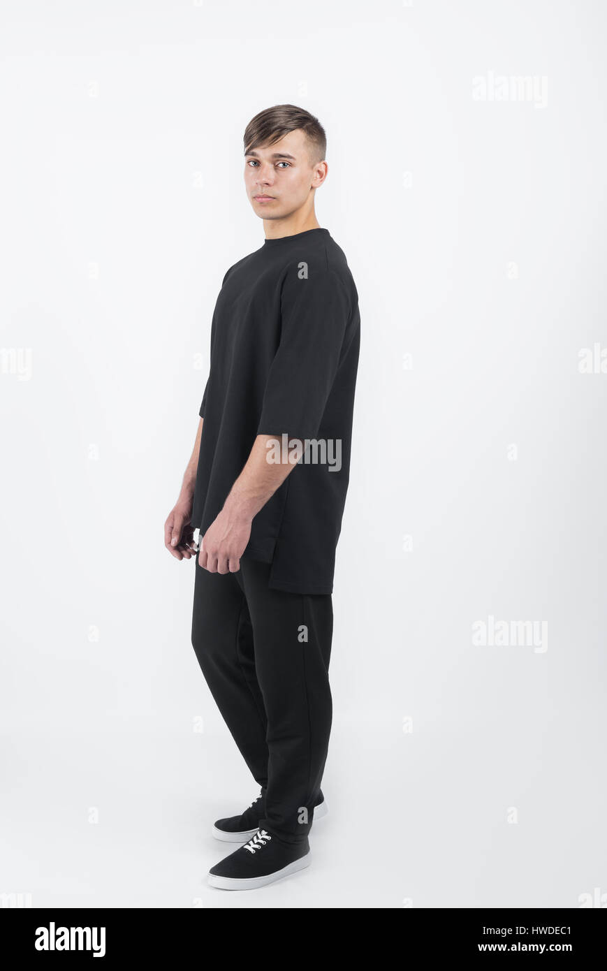 Young muscular man wearing black clothes and sneakers on white background Stock Photo