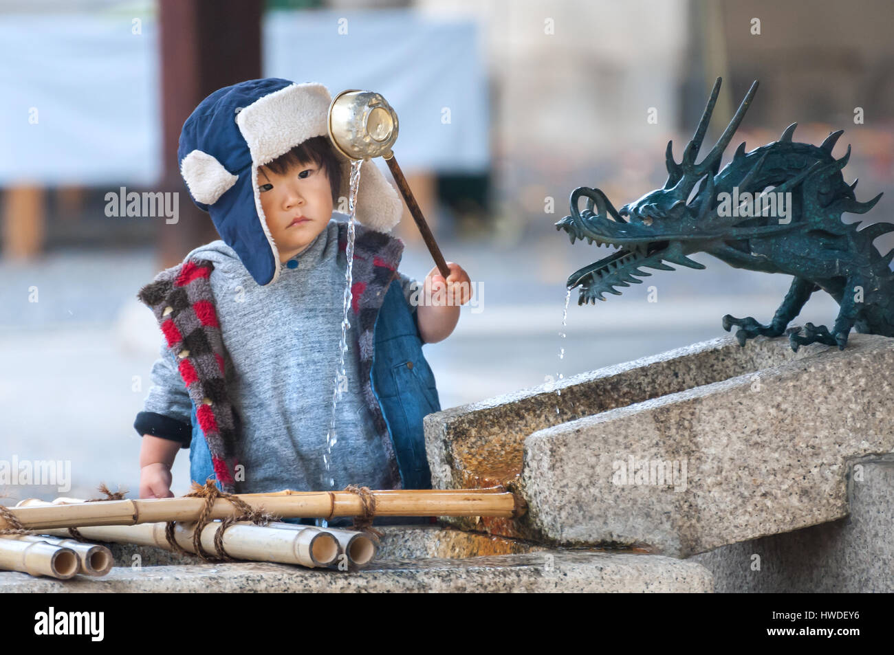 KYOTO, JAPAN - NOV 2016 - A young boy scoops water out of a purification fountain at a temple in Kyoto, Japan Stock Photo
