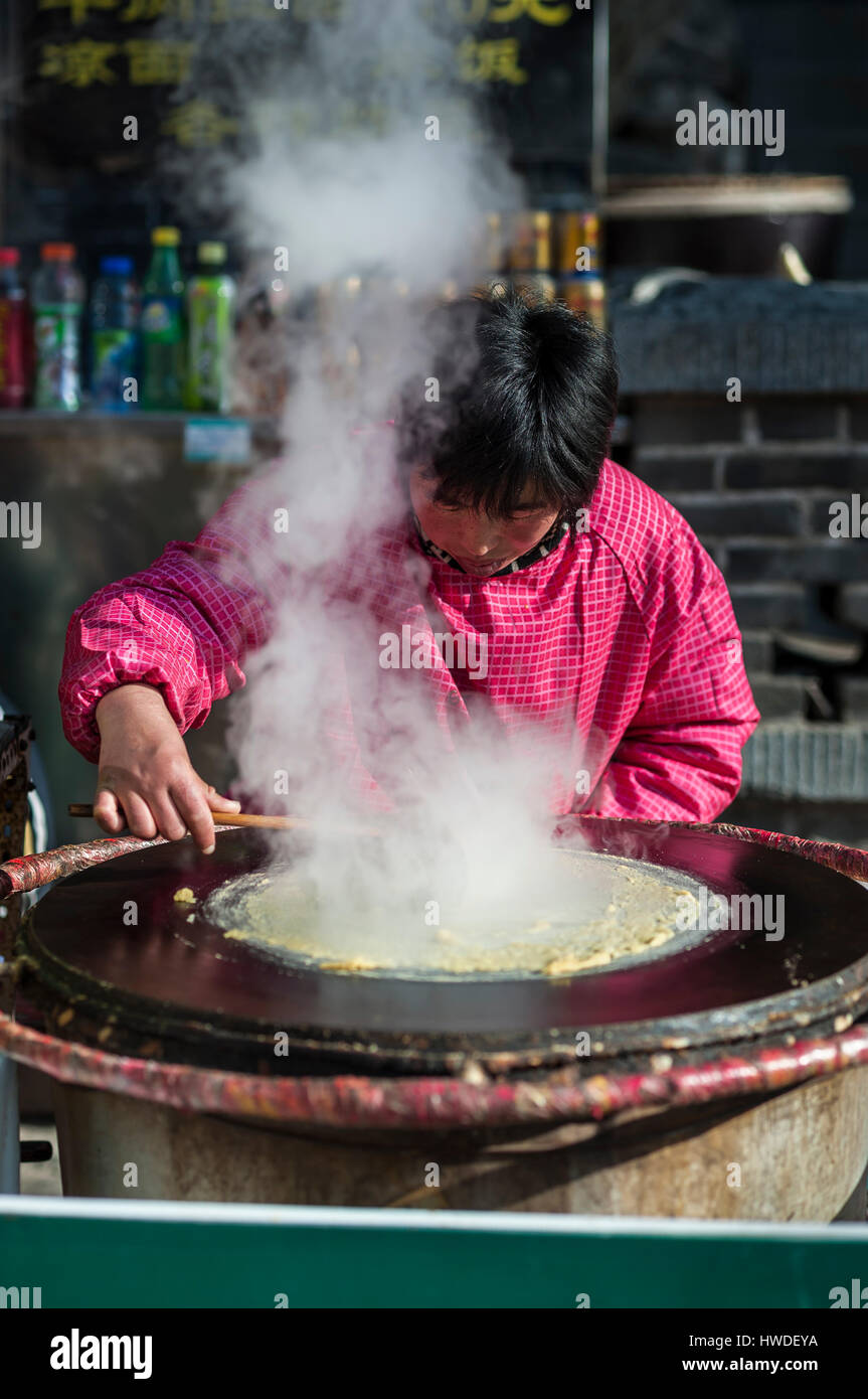 TAISHAN, CHINA - JAN 2014 - A woman prepares a traditional Shandong pancake (jianbing) on taishan mountain, Shandong Province, China Stock Photo