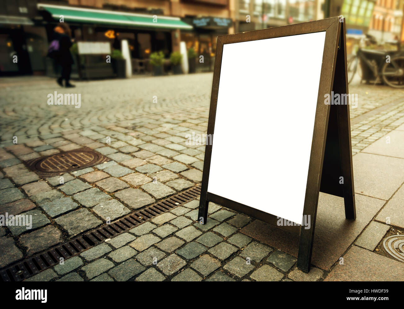 Blank restaurant advertising board as copy space on the street. Angled freestanding A-frame blackboard for mockup design. Stock Photo