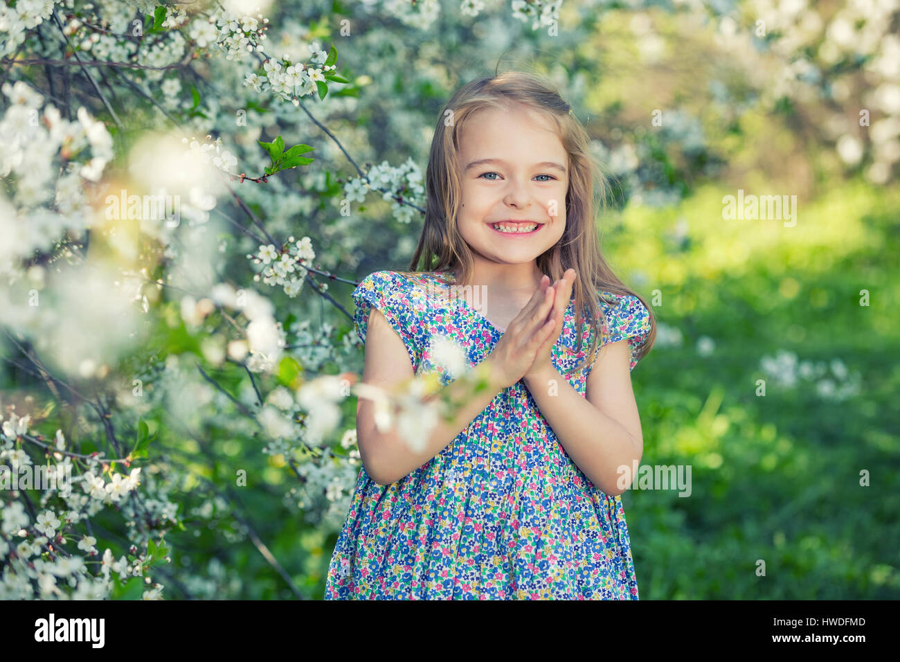 Happy little girl in cherry blossom garden Stock Photo - Alamy