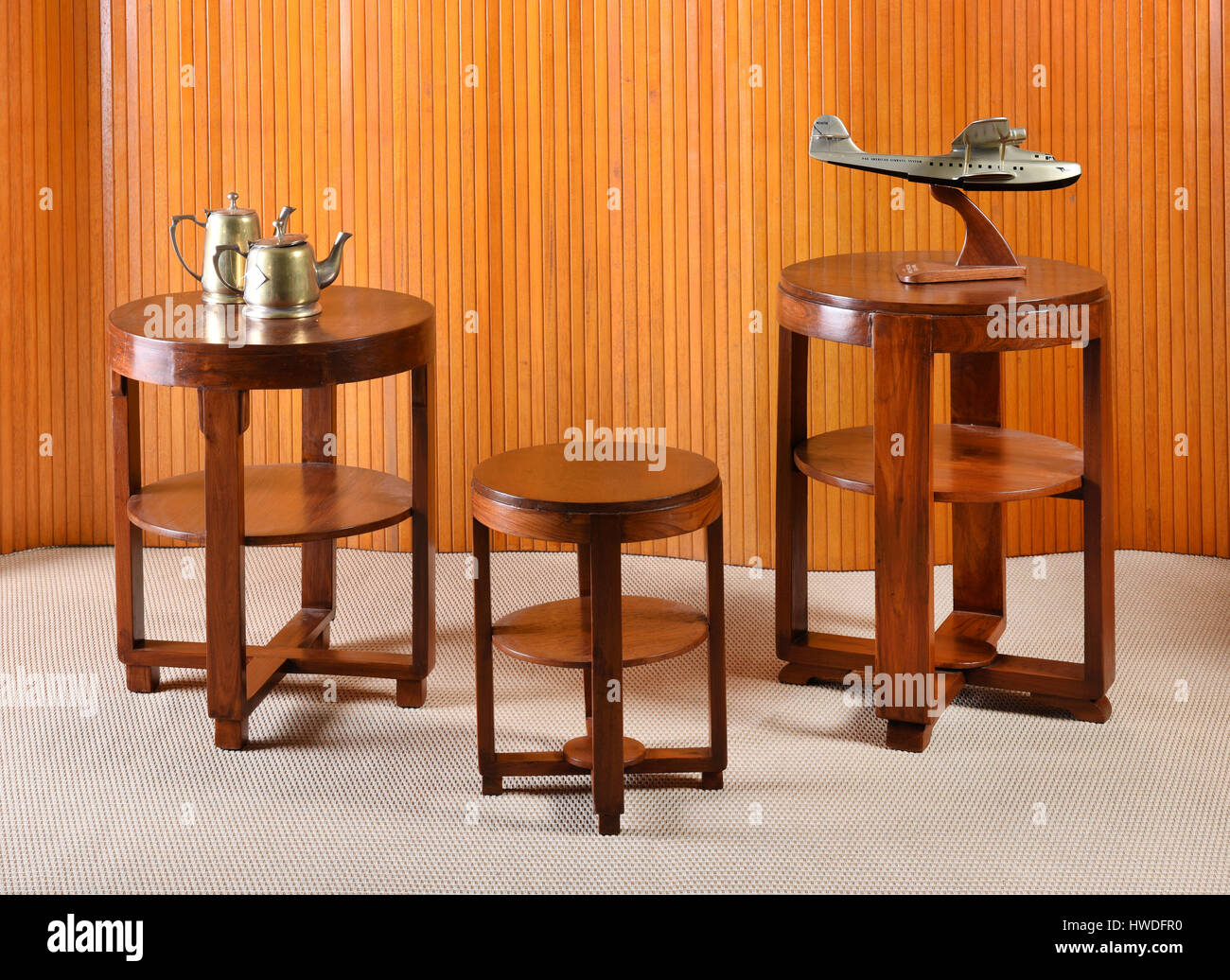 Brass tea pots and airplane sculptures on set of three round wooden tables Stock Photo