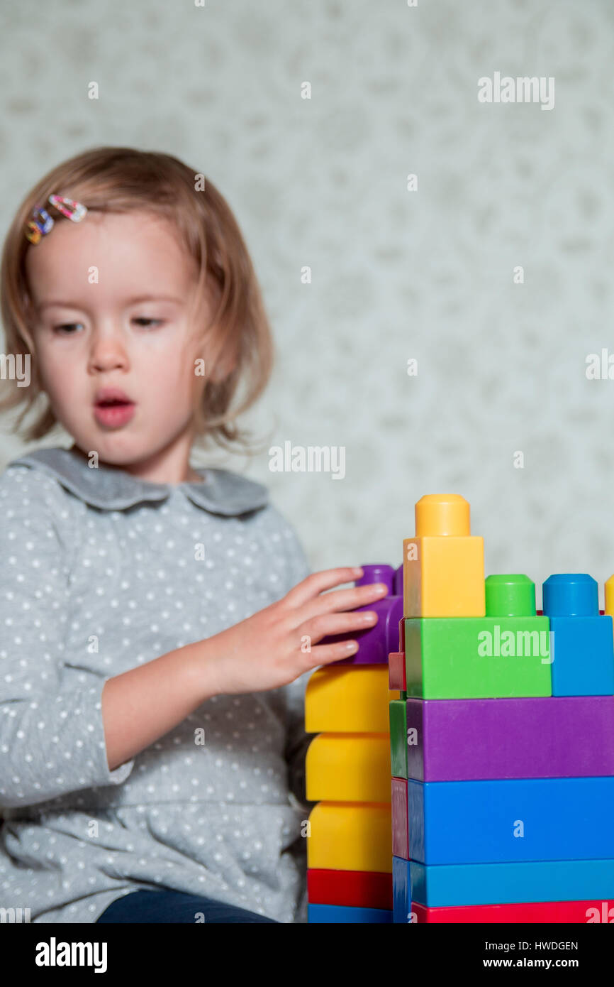 Child girl having fun and build of bright plastic construction blocks ...