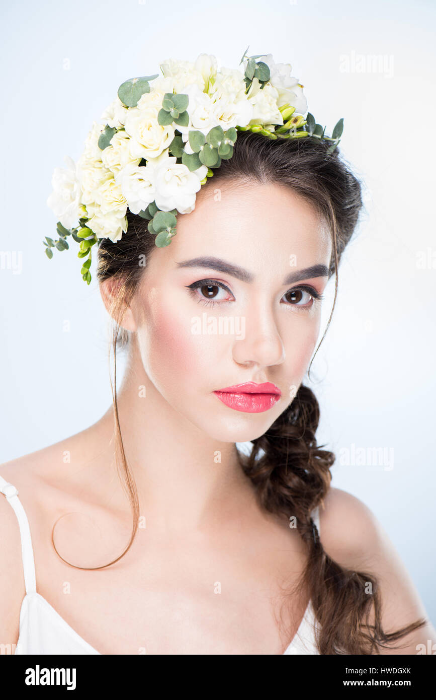 portrait of serious woman with flowers in hair on white Stock Photo