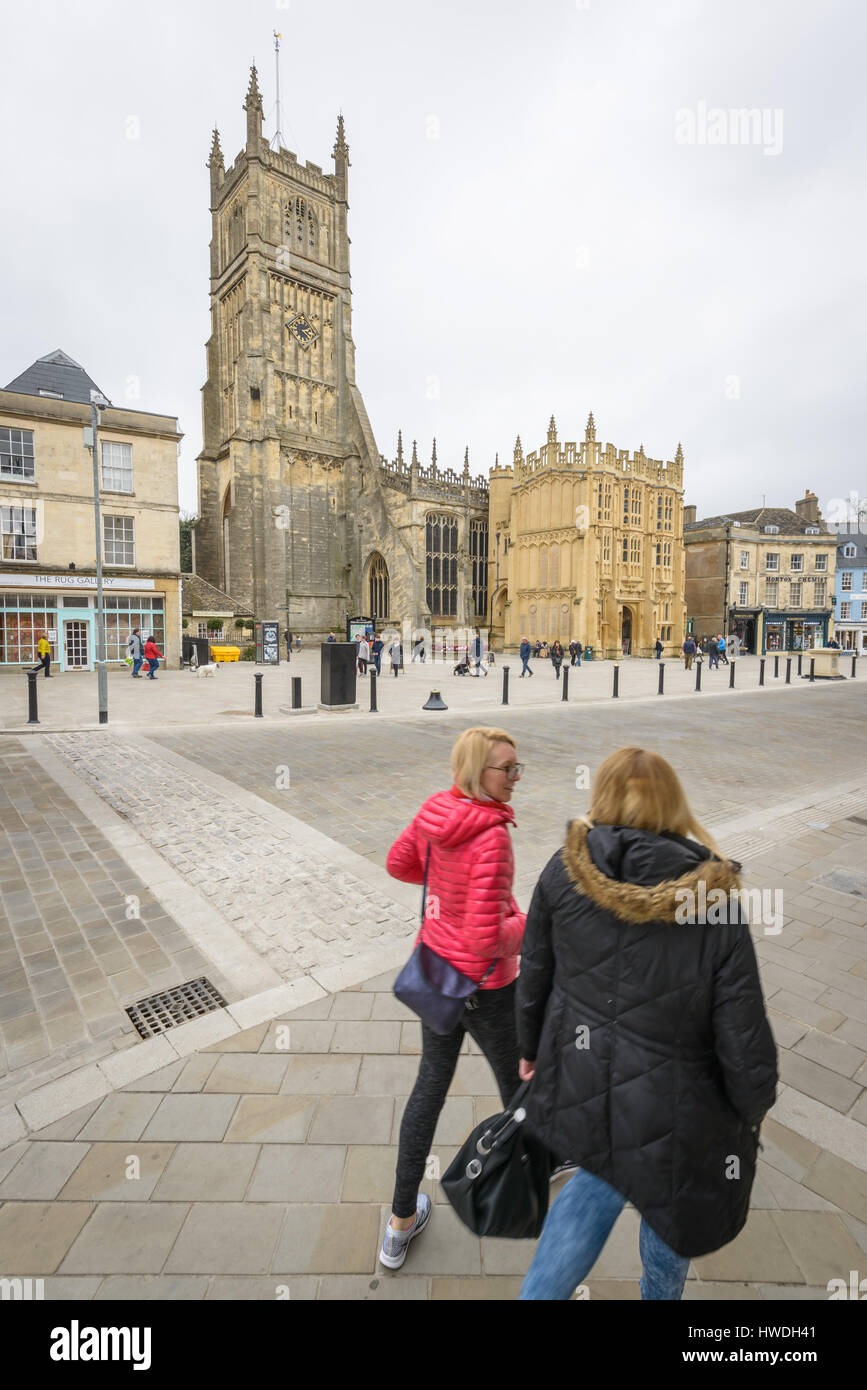 People walk around Market Square in front of St John the Baptist parish church, Cirencester in the Cotswolds, Gloucester, England, UK Stock Photo
