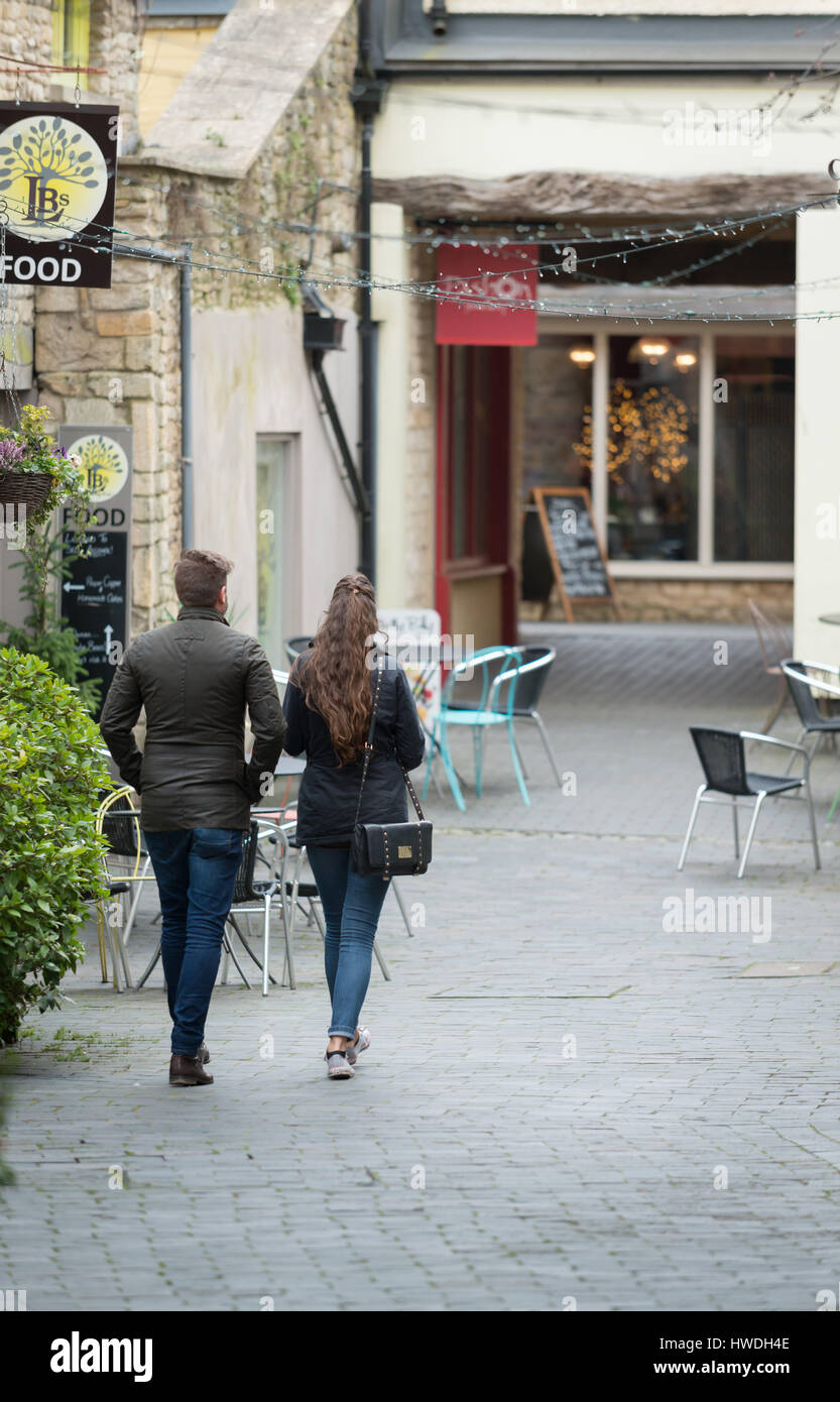 A young man and woman walk through Swan Yard looking at the shops, Cirencester in the Cotswolds, Gloucester, England, UK Stock Photo