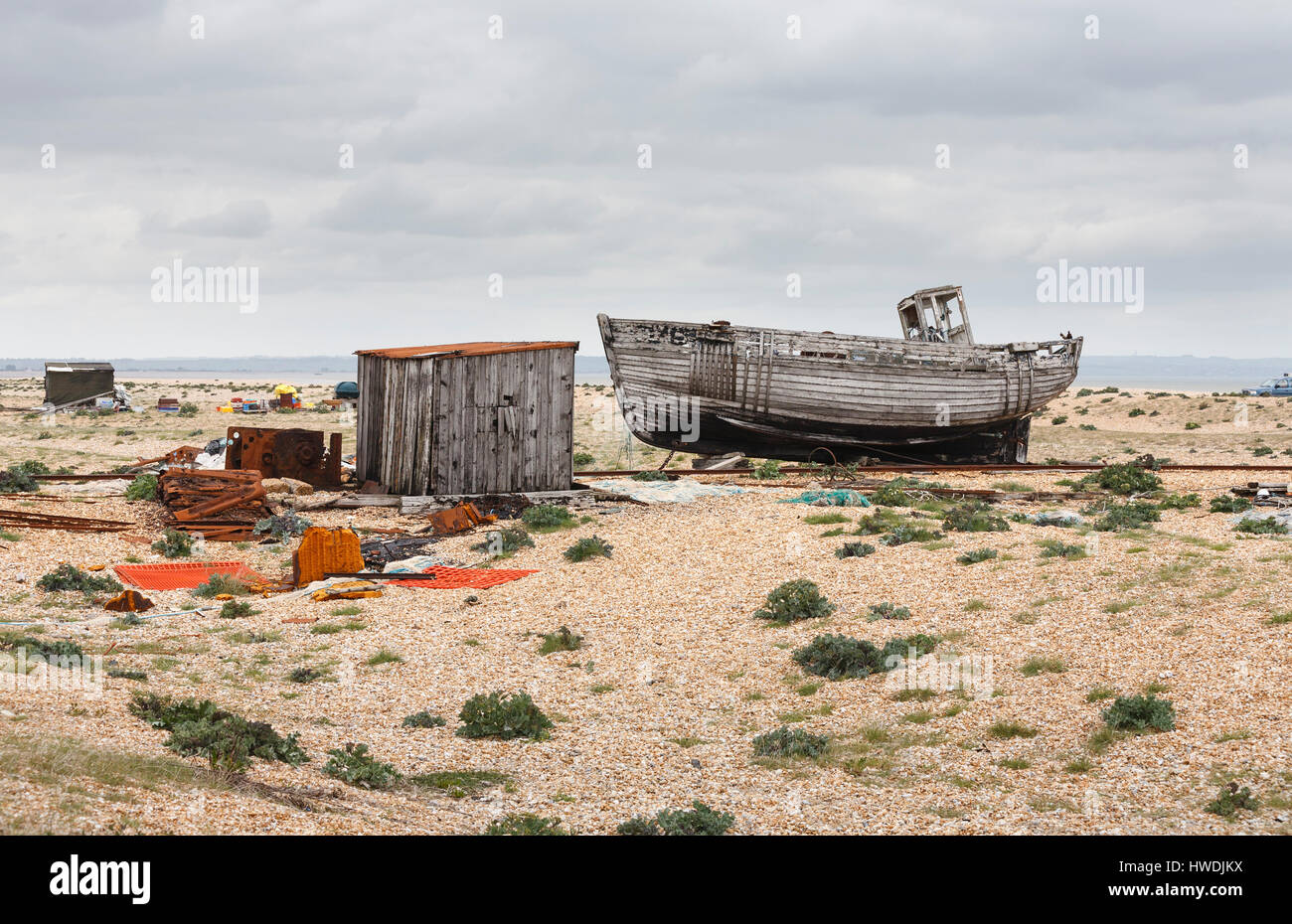 Abandoned, rotting wooding fishing boat and equipment on the bleak shingle beach seashore at Dungeness, Shepway district, Kent Stock Photo