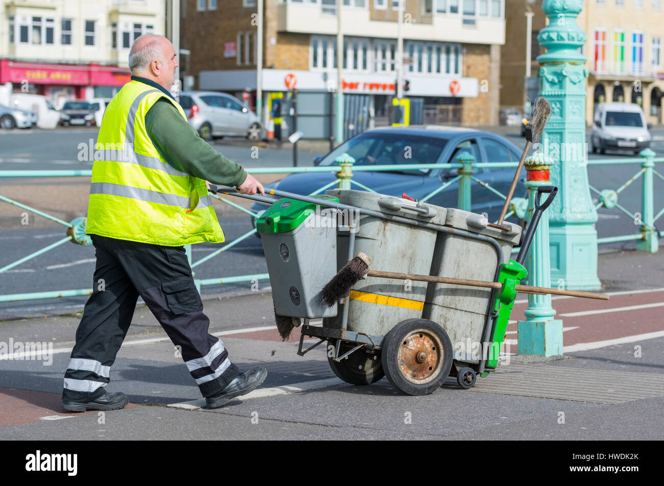 Male council street cleaner pushing a little bin in Brighton, East