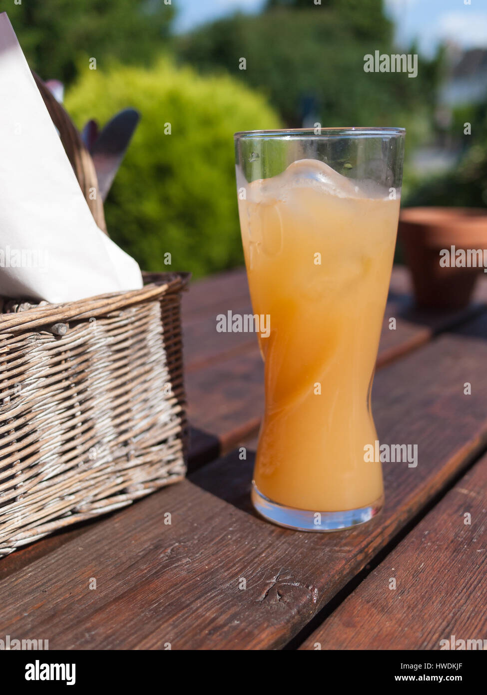 Cold refreshing drink of orange on a warm sunny day on a wooden bench. Stock Photo