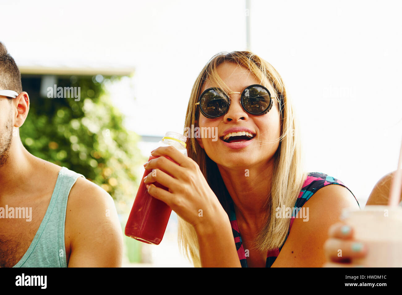 Male and female friends relaxing with drinks in park Stock Photo - Alamy