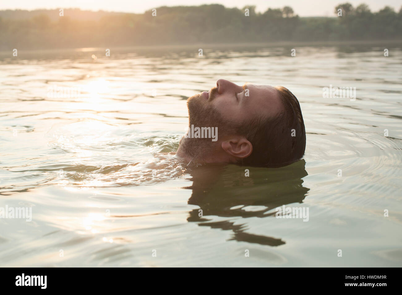 Man relaxing, floating in river Stock Photo