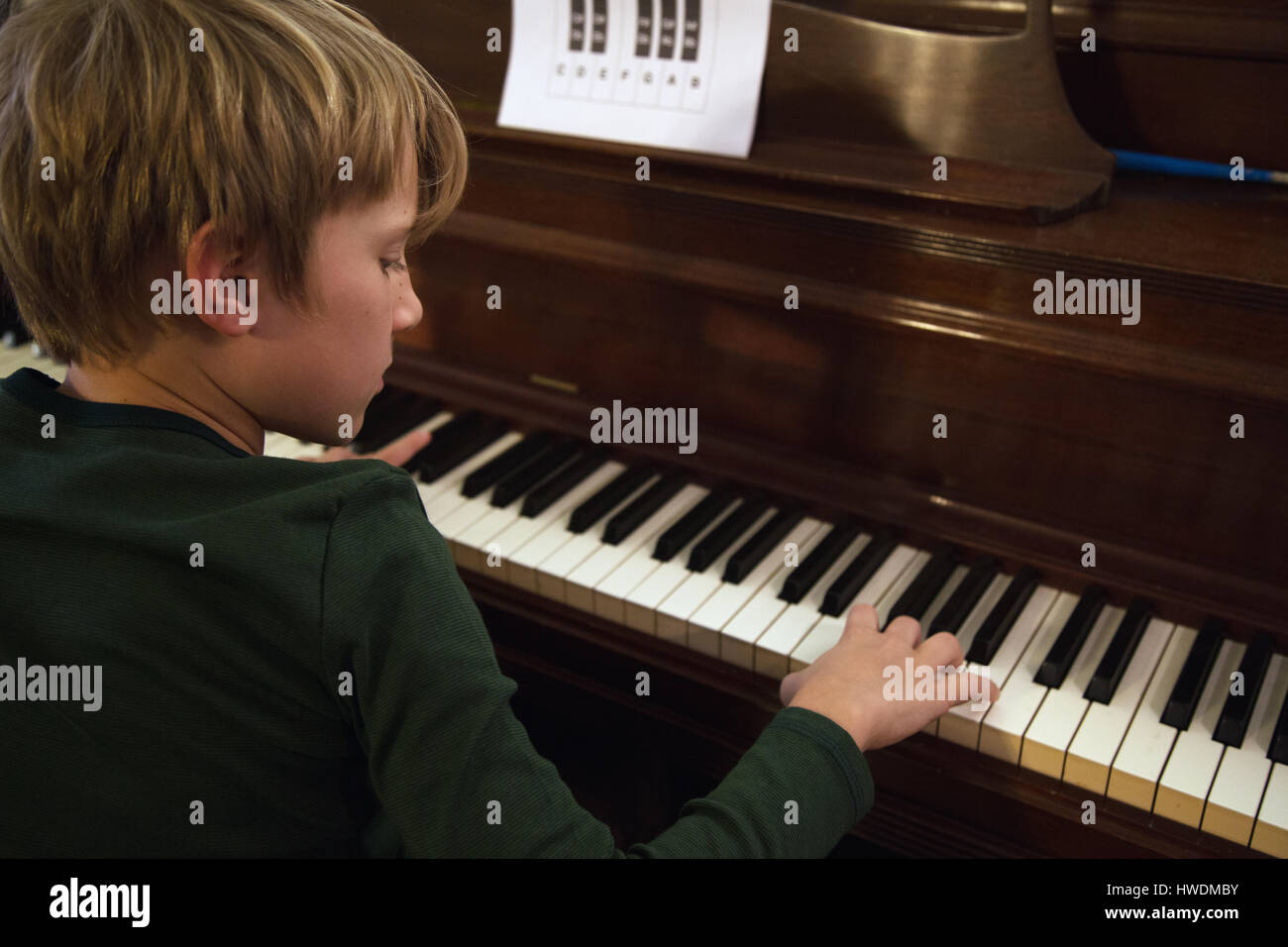 Over shoulder view of boy playing piano in living room Stock Photo Alamy