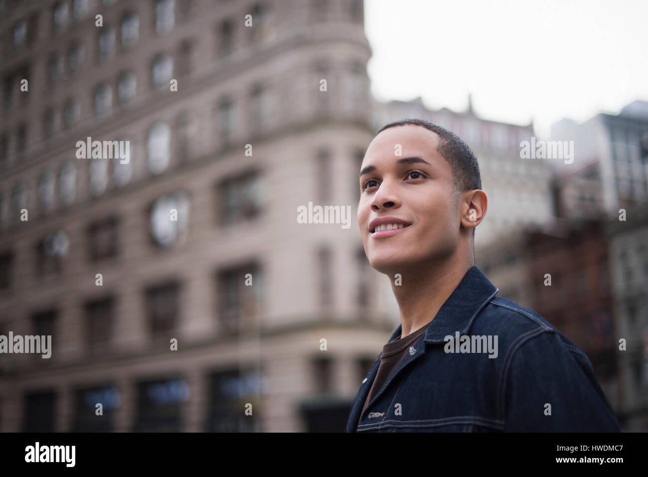 Young man standing in street, Flatiron Building in background, Manhattan, New York, USA Stock Photo