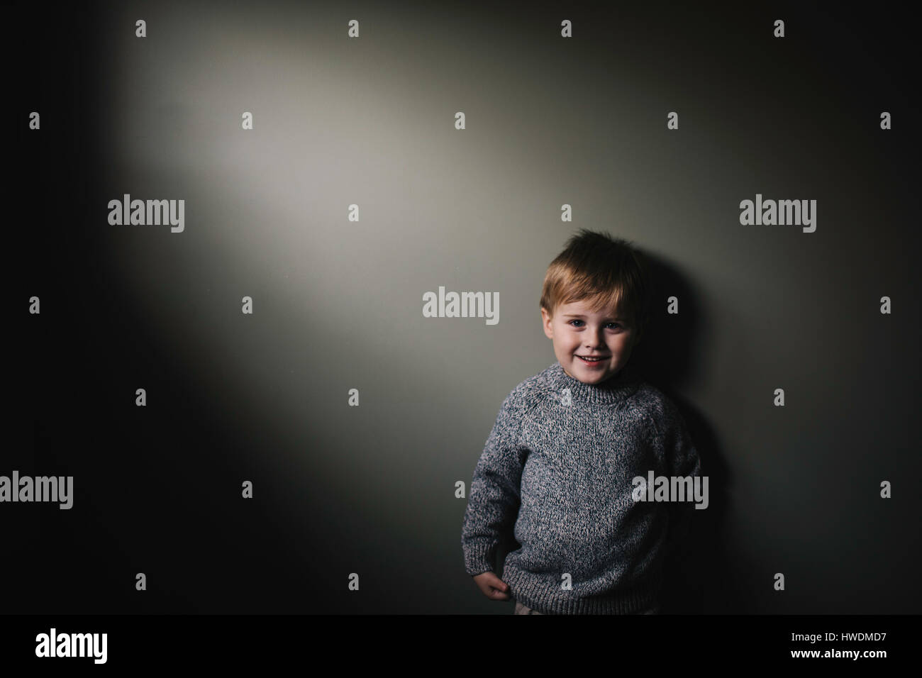 Portrait of young boy against grey background, smiling Stock Photo