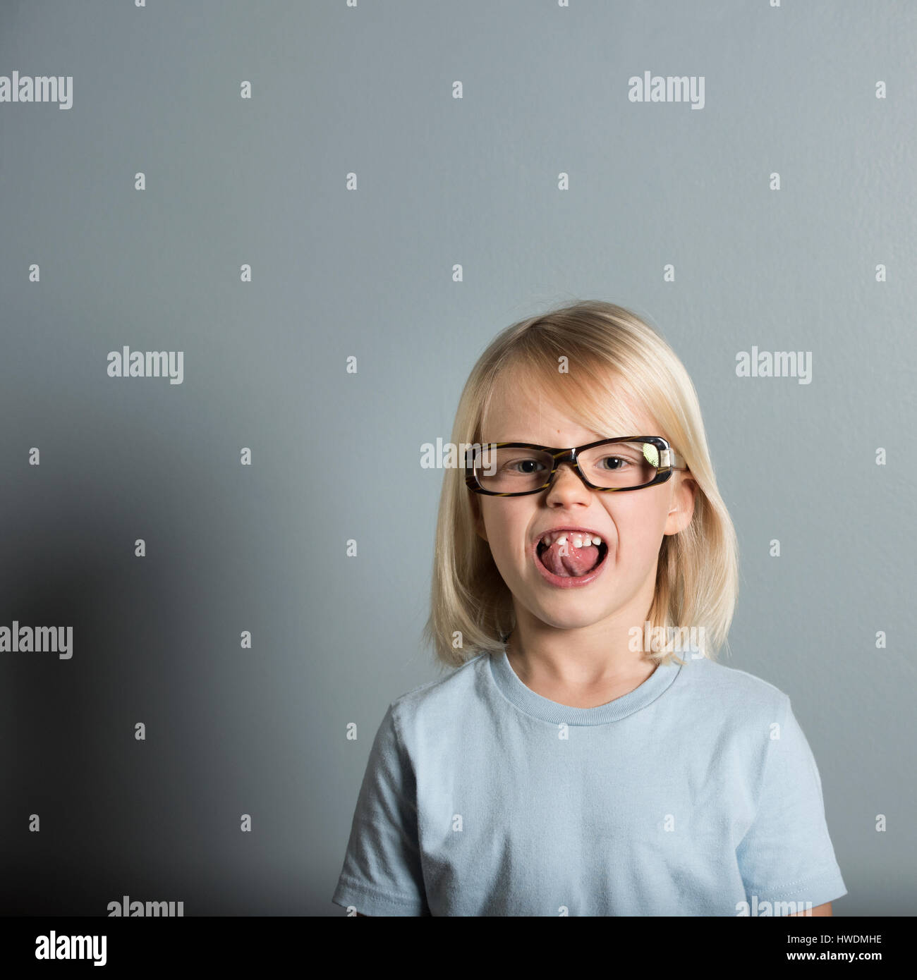 Portrait of boy wearing glasses sticking out tongue Stock Photo