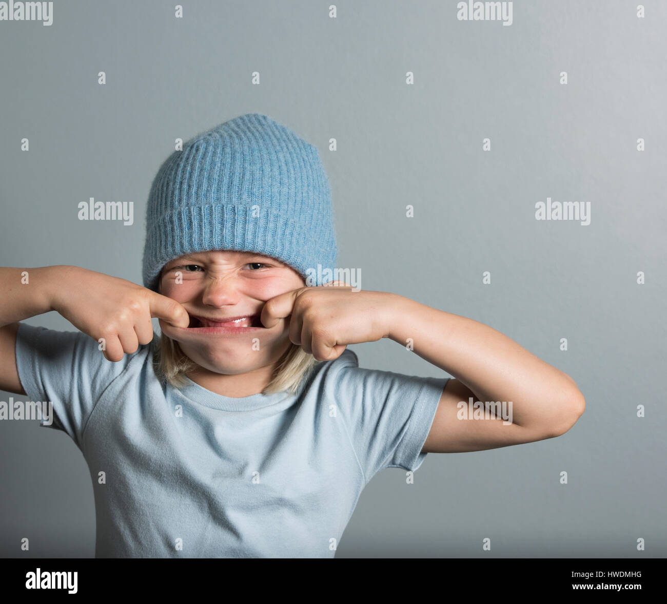 Portrait of boy with fingers in mouth pulling face Stock Photo
